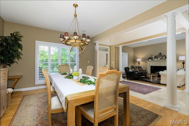1001 Laurel Bend Ct S, Kirkwood, MO 63122 - dining space featuring decorative columns, a chandelier, a fireplace, and light wood-style flooring