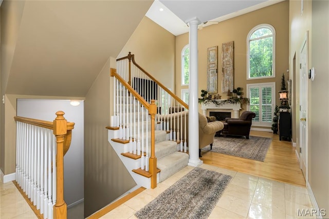 1001 Laurel Bend Ct S, Kirkwood, MO 63122 - stairs featuring decorative columns, a fireplace, a towering ceiling, and wood finished floors