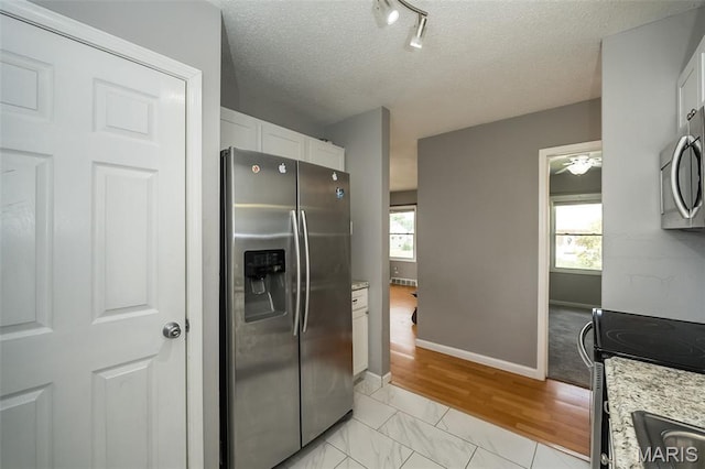 4322 Heidelberg Ave, Saint Louis, MO 63123 - kitchen featuring stainless steel appliances, white cabinets, track lighting, a textured ceiling, and light stone countertops