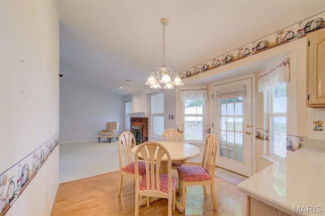 1733 Forest Trace Dr, Ofallon, MO 63368 - dining room featuring a chandelier, light wood-style flooring, and a brick fireplace
