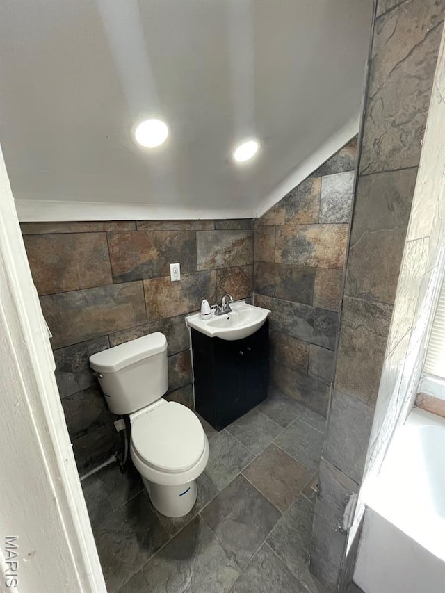 5350 Claxton Ave, Saint Louis, MO 63120 - bathroom featuring a tub to relax in, tile walls, vanity, recessed lighting, and stone finish flooring