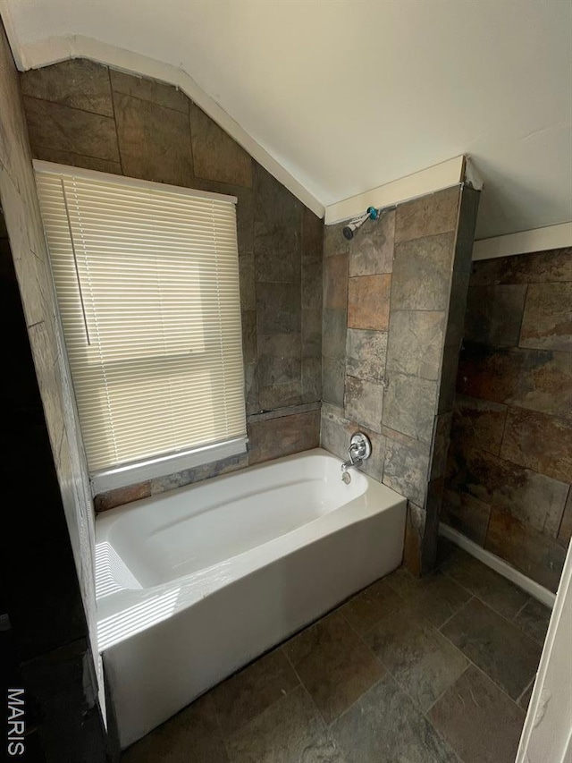 5350 Claxton Ave, Saint Louis, MO 63120 - bathroom featuring a bathtub, lofted ceiling, stone tile flooring, and tiled shower