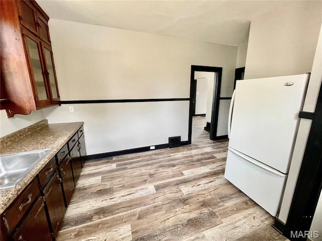 1519 Lebanon Ave, Belleville, IL 62221 - kitchen with freestanding refrigerator, light wood-style flooring, glass insert cabinets, and dark brown cabinetry