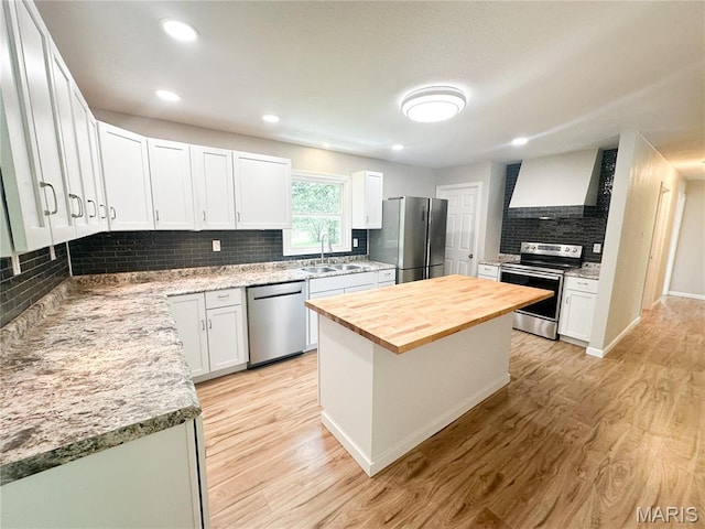66 County Road 6680, Salem, MO 65560 - kitchen featuring appliances with stainless steel finishes, butcher block counters, custom range hood, tasteful backsplash, and light wood-type flooring