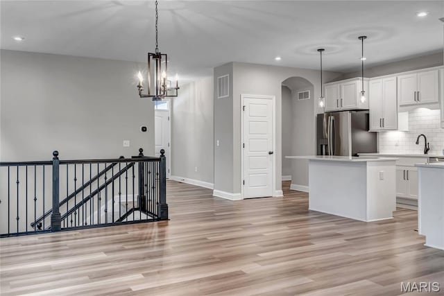 211 Cambium Ct, Wentzville, MO 63385 - kitchen featuring stainless steel refrigerator with ice dispenser, arched walkways, recessed lighting, a center island, and backsplash