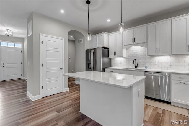 211 Cambium Ct, Wentzville, MO 63385 - kitchen with appliances with stainless steel finishes, arched walkways, light wood-style floors, decorative backsplash, and recessed lighting