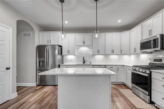 211 Cambium Ct, Wentzville, MO 63385 - kitchen featuring appliances with stainless steel finishes, a center island, light wood-type flooring, decorative backsplash, and recessed lighting
