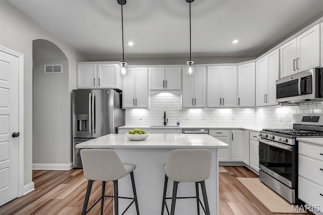 211 Cambium Ct, Wentzville, MO 63385 - kitchen with appliances with stainless steel finishes, a breakfast bar area, light wood-style flooring, light countertops, and recessed lighting
