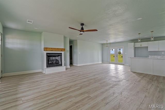 3120 State Highway F, Cardwell, MO 63829 - unfurnished living room with light wood finished floors, a fireplace with raised hearth, ceiling fan, a textured ceiling, and french doors