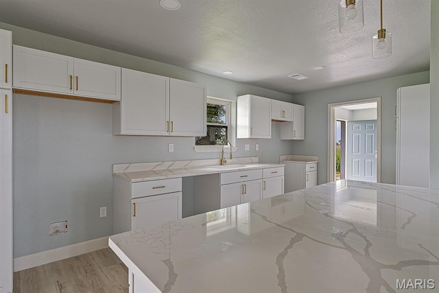 3120 State Highway F, Cardwell, MO 63829 - kitchen featuring white cabinetry, light stone countertops, light wood-type flooring, a textured ceiling, and recessed lighting