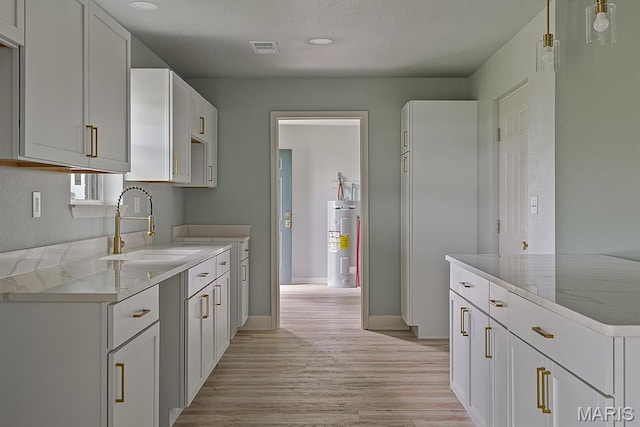 3120 State Highway F, Cardwell, MO 63829 - kitchen featuring water heater, light wood finished floors, white cabinets, light stone countertops, and recessed lighting