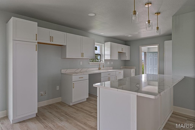 3120 State Highway F, Cardwell, MO 63829 - kitchen with white cabinets, a peninsula, light wood finished floors, a textured ceiling, and light countertops