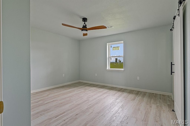 3120 State Highway F, Cardwell, MO 63829 - spare room featuring a barn door, light wood-style floors, and ceiling fan