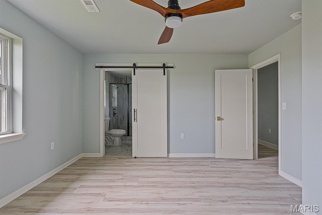 3120 State Highway F, Cardwell, MO 63829 - unfurnished bedroom featuring light wood-style flooring, a barn door, ensuite bath, and ceiling fan
