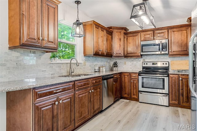 404 Arbor Spring Dr, Ballwin, MO 63021 - kitchen featuring appliances with stainless steel finishes, light wood-style floors, light stone counters, and brown cabinets