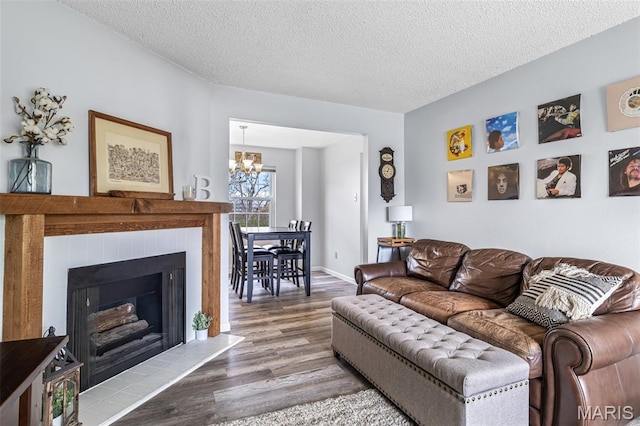 2318 Hidden Meadow Ln, Ballwin, MO 63021 - living area featuring wood finished floors, a chandelier, a textured ceiling, and a tile fireplace