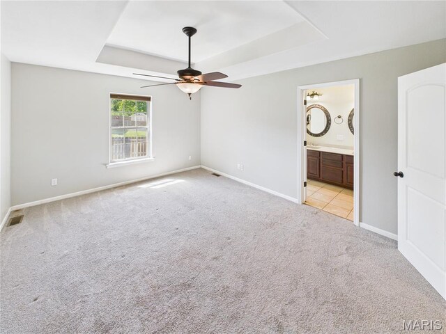 16107 Hummingbird Ln, Saint Robert, MO 65584 - unfurnished bedroom with a tray ceiling, carpet, connected bathroom, and a ceiling fan