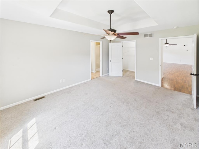 16107 Hummingbird Ln, Saint Robert, MO 65584 - unfurnished bedroom featuring a tray ceiling, light colored carpet, a spacious closet, and ceiling fan