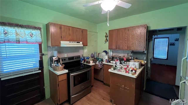 812 S Mine Ln, Motte, Fredericktown, MO 63645 - kitchen with stainless steel range with electric stovetop, under cabinet range hood, light countertops, ceiling fan, and light wood finished floors