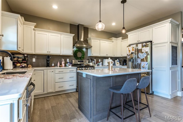 3841 Ember Ct, Edwardsville, IL 62025 - kitchen with wall chimney exhaust hood, stainless steel appliances, wood finished floors, light countertops, and backsplash