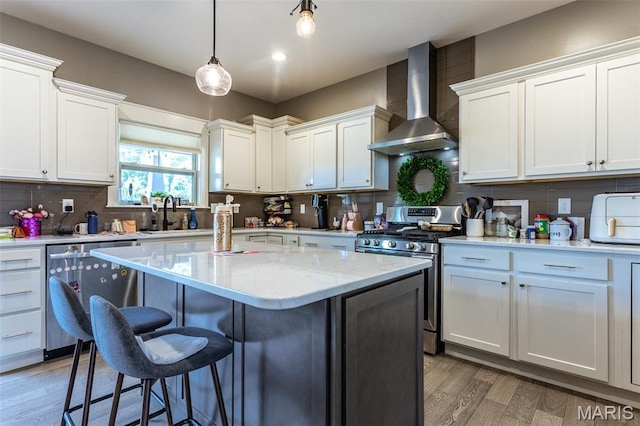 3841 Ember Ct, Edwardsville, IL 62025 - kitchen with wall chimney exhaust hood, stainless steel appliances, a kitchen breakfast bar, light wood-type flooring, and a kitchen island