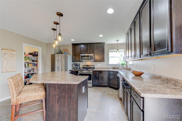 606 Wyndview Dr, Lake St Louis, MO 63367 - kitchen featuring appliances with stainless steel finishes, dark brown cabinetry, a center island, pendant lighting, and a breakfast bar