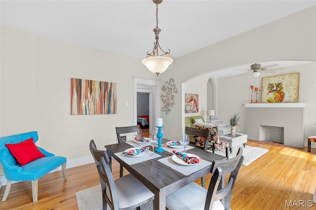 3119 Tamm Ave, Saint Louis, MO 63139 - dining space featuring wood finished floors, arched walkways, ceiling fan, and a brick fireplace