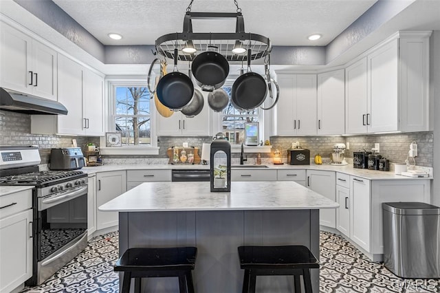 402 S Walker St, Montgomery City, MO 63361 - kitchen with stainless steel appliances, under cabinet range hood, healthy amount of natural light, a textured ceiling, and a kitchen bar
