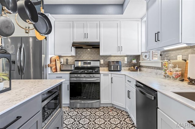 402 S Walker St, Montgomery City, MO 63361 - kitchen featuring stainless steel appliances, under cabinet range hood, tasteful backsplash, and white cabinetry