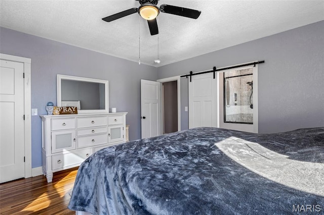 402 S Walker St, Montgomery City, MO 63361 - bedroom with a barn door, wood finished floors, a textured ceiling, and ceiling fan
