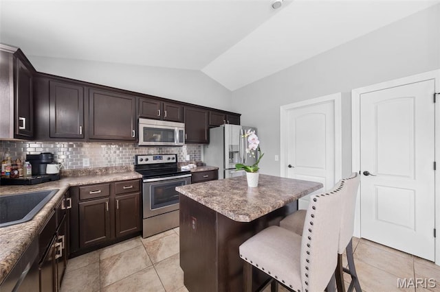80 Brookshire Creek Dr, Wentzville, MO 63385 - kitchen featuring appliances with stainless steel finishes, vaulted ceiling, a kitchen bar, dark brown cabinets, and backsplash