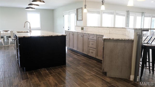 3215 Timber Ridge Rd, Palmyra, MO 63461 - kitchen with a kitchen island with sink, dark wood-type flooring, light stone countertops, a breakfast bar, and pendant lighting