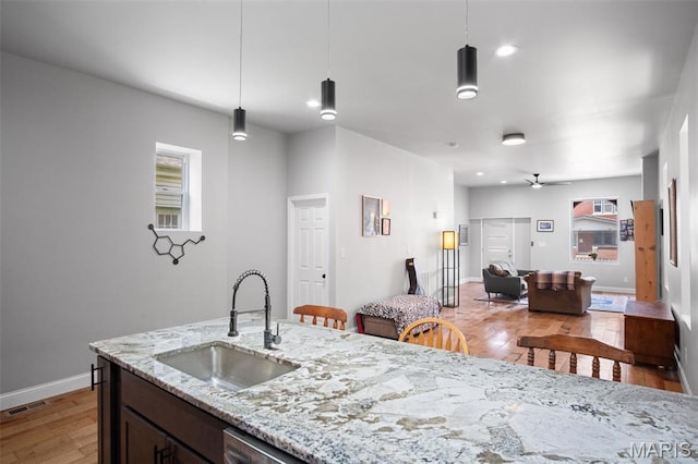 3452 Osage St, Saint Louis, MO 63118 - kitchen featuring light wood finished floors, a ceiling fan, pendant lighting, light stone countertops, and dark brown cabinetry