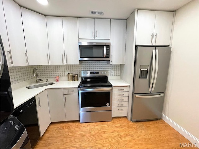 1418 Bluebird Ter, Saint Louis, MO 63144 - kitchen with appliances with stainless steel finishes, light wood finished floors, tasteful backsplash, and light countertops