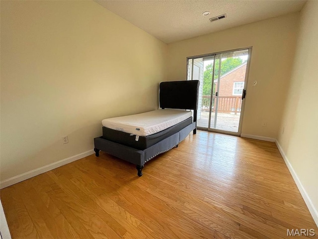1418 Bluebird Ter, Saint Louis, MO 63144 - bedroom with access to exterior, light wood-style floors, and a textured ceiling