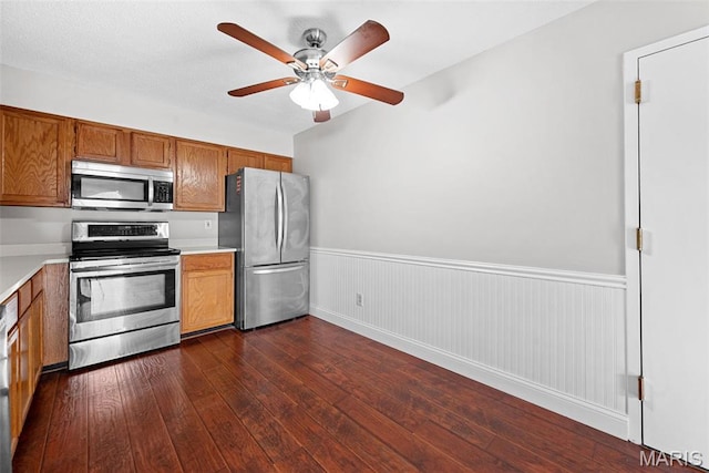 2 Berview Cir Unit H, Saint Louis, MO 63129 - kitchen with appliances with stainless steel finishes, light countertops, brown cabinets, ceiling fan, and a wainscoted wall
