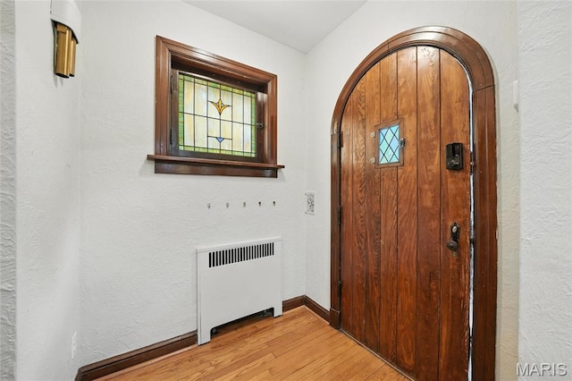 5743 Delor St, Saint Louis, MO 63109 - foyer entrance with radiator, light wood-style floors, arched walkways, and a textured wall