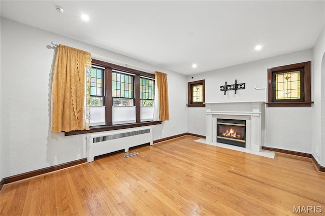 5743 Delor St, Saint Louis, MO 63109 - unfurnished living room with radiator heating unit, light wood-style floors, a fireplace with flush hearth, and recessed lighting