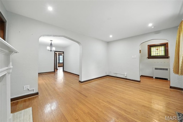 5743 Delor St, Saint Louis, MO 63109 - unfurnished living room with radiator, arched walkways, light wood finished floors, a chandelier, and recessed lighting