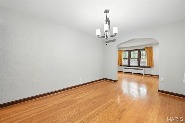 5743 Delor St, Saint Louis, MO 63109 - spare room with radiator, arched walkways, wood finished floors, and a chandelier