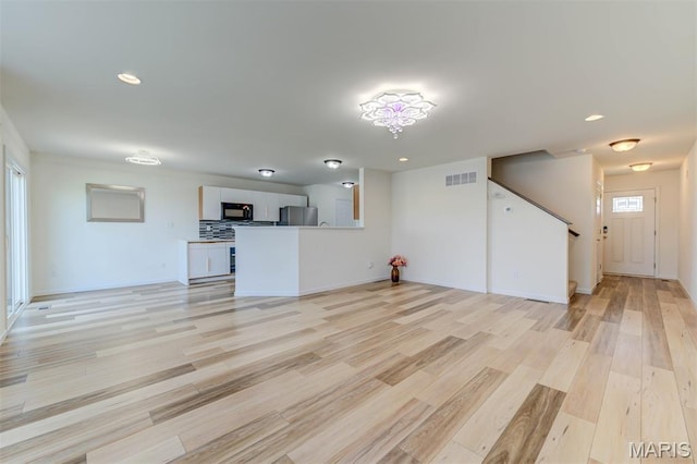 502 Summer Glen Ln, Saint Charles, MO 63301 - unfurnished living room with light wood-style flooring, recessed lighting, and stairway