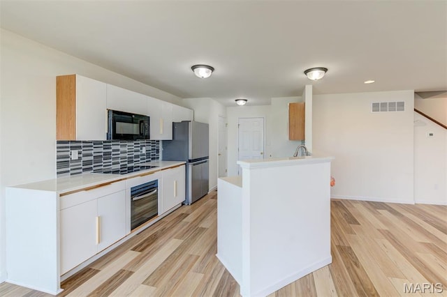 502 Summer Glen Ln, Saint Charles, MO 63301 - kitchen with black appliances, light wood-style floors, light countertops, and backsplash