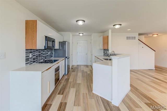 502 Summer Glen Ln, Saint Charles, MO 63301 - kitchen with black appliances, decorative backsplash, light countertops, and light wood finished floors