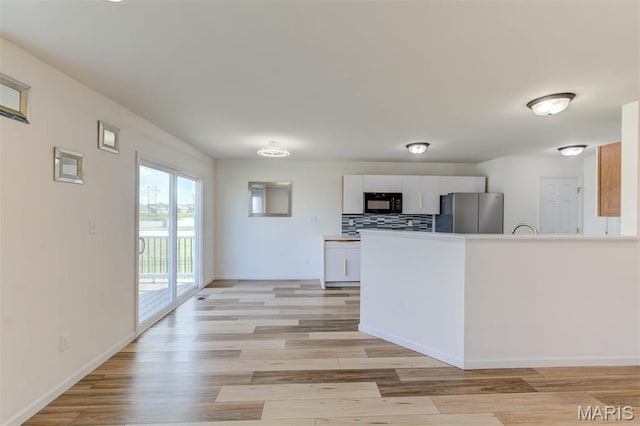 502 Summer Glen Ln, Saint Charles, MO 63301 - kitchen featuring freestanding refrigerator, black microwave, white cabinets, and light wood-style flooring