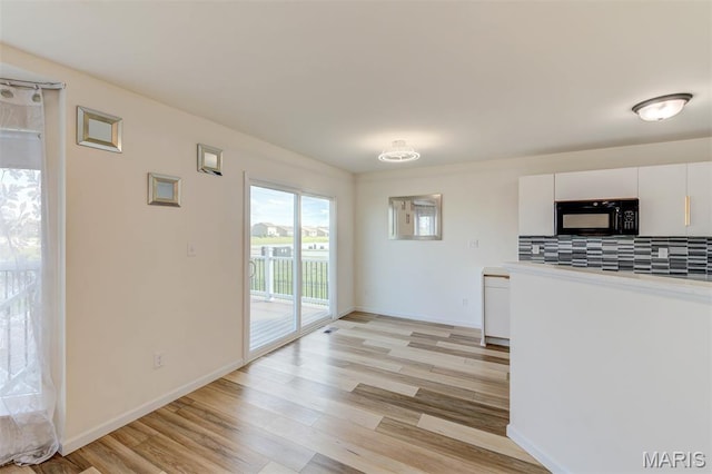 502 Summer Glen Ln, Saint Charles, MO 63301 - kitchen with black microwave, backsplash, light wood-type flooring, white cabinets, and light countertops