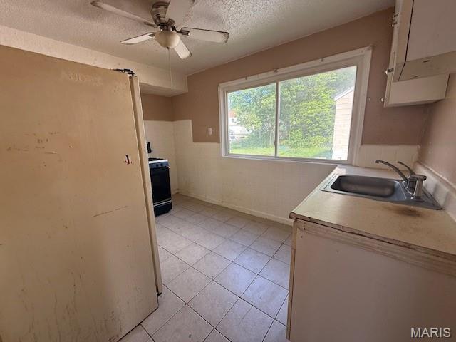 7446 Calvin Ave, Country Club Hills, MO 63136 - kitchen with range with electric cooktop, a textured ceiling, ceiling fan, white cabinetry, and light tile patterned flooring
