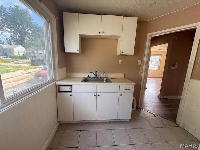 7446 Calvin Ave, Country Club Hills, MO 63136 - kitchen with light countertops, white cabinets, light tile patterned floors, and a textured ceiling
