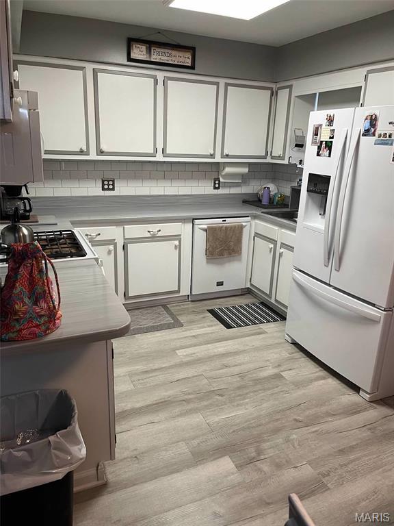 746 State Highway P, New Madrid, MO 63869 - kitchen featuring white appliances, decorative backsplash, white cabinetry, light wood-style flooring, and light countertops