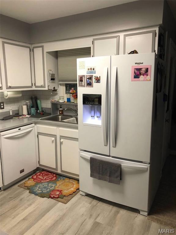 746 State Highway P, New Madrid, MO 63869 - kitchen with white appliances, light wood-style flooring, white cabinetry, and backsplash