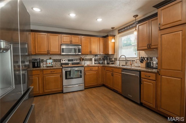 16533 Chateau Ln, Dexter, MO 63841 - kitchen with appliances with stainless steel finishes, brown cabinetry, backsplash, wood finished floors, and a textured ceiling